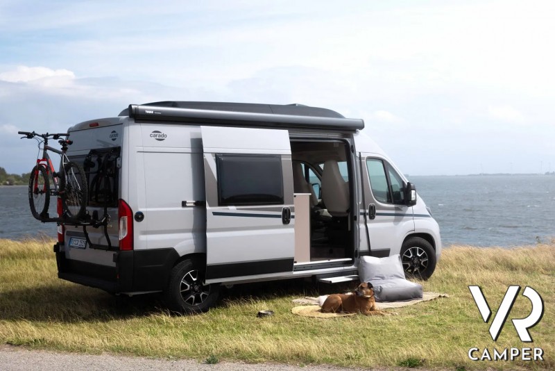 camper furgonato con portabici su prato paesaggio
